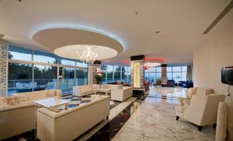 a large , modern living room with white couches , chairs , and a dining table in the background at Q Premium Resort