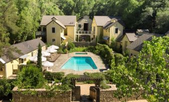 a beautiful yellow house surrounded by trees , with a swimming pool in the foreground , creating a serene and inviting atmosphere at Farmhouse Inn
