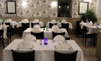 a well - decorated dining room with several tables covered in white tablecloths and adorned with purple napkins at Hob le Cheval Blanc