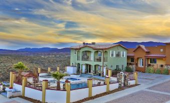 a large , two - story house with a swimming pool and a beautiful sunset in the background at Dream Manor Inn