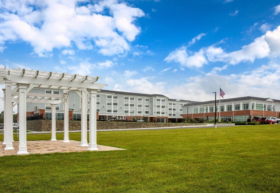 a large white building with a pergola in front of it , surrounded by a grassy field at Wyndham Newport Hotel