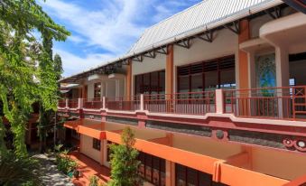 a large , multi - story building with orange and white walls and a red roof , surrounded by trees and other buildings at Hotel Elvin