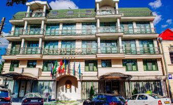 a large hotel building with multiple flags and banners on the front , surrounded by cars parked outside at Savoy Hotel