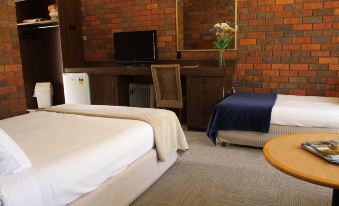 a room with two beds , a tv on the wall , and a vase of flowers at Bonnie Doon Hotel