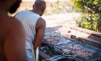 a man is standing next to a barbecue grill , preparing to cook meat on it at Asia Resort