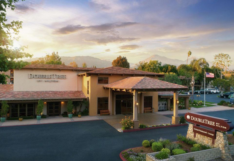 an exterior view of a building , possibly a hotel , with a large sign above the entrance at DoubleTree by Hilton Claremont