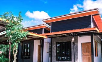a modern house with a red roof and white walls is shown against a blue sky at Khun Naparn Resort
