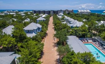 aerial view of a residential area with multiple houses and a dirt road surrounded by trees at Magnolia Cottages by the Sea by Panhandle Getaways