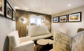 a modern living room with white sofas , a coffee table , and framed art on the walls at Sofitel London Gatwick