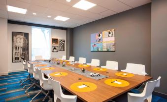 a conference room with a long wooden table , multiple chairs , and a large painting on the wall at Aloft Miami Dadeland
