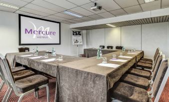 "a conference room with a large table , chairs , and a projector screen displaying the word "" mercur "" on it" at Mercure Paris Ivry Quai de Seine