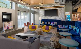 a modern living room with various seating options , including couches , chairs , and a dining table at Aloft Chapel Hill