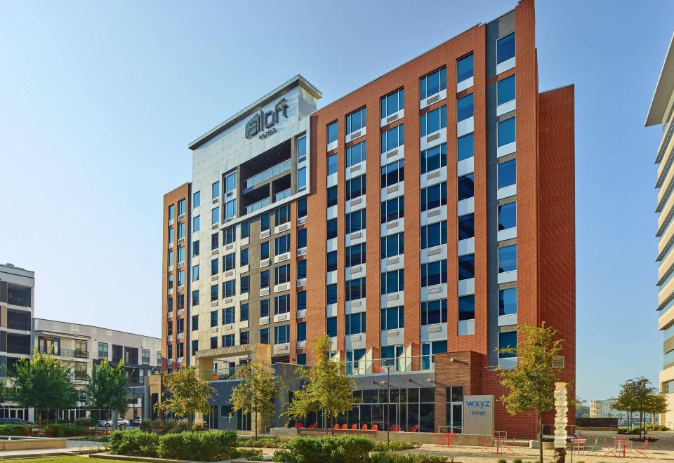 "a large , modern office building with the word "" aloft "" prominently displayed on its side" at Aloft Richardson