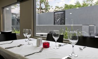 a dining table set for a meal , with wine glasses and utensils arranged on the table at Argus Hotel Darwin