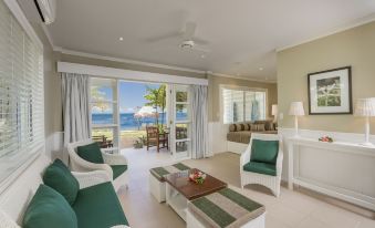 a living room with a couch , chairs , and a coffee table is shown with an ocean view at Malolo Island Resort