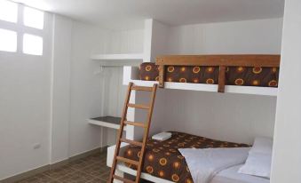 a bunk bed with a ladder is in a room with white walls and a window at Costa Esmeralda