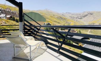 a balcony with a chair and a table , overlooking a mountainous landscape under a clear blue sky at Bellevue