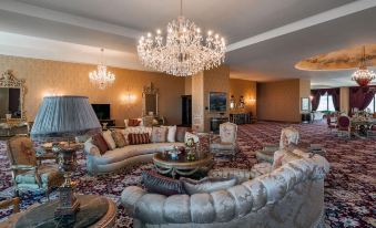 a luxurious living room with a large chandelier , multiple couches , and a chandelier hanging from the ceiling at Quba Palace Hotel & Golf Resort