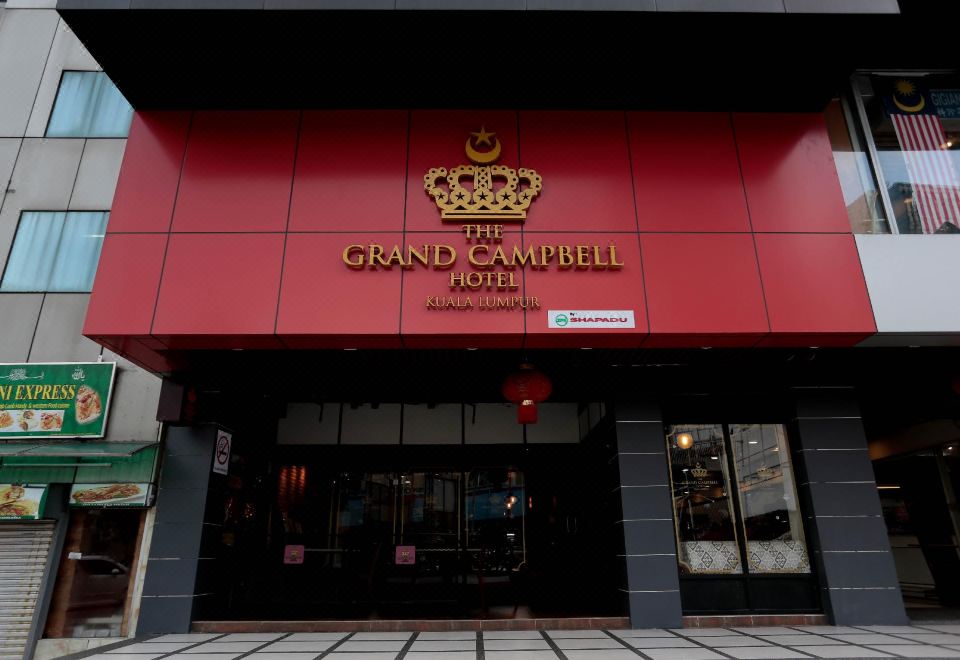 The front entrance of a restaurant is adorned with an oriental sign, while another building stands nearby at The Grand Campbell Hotel Kuala Lumpur