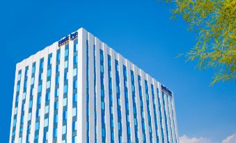 a tall , modern building with a blue and white color scheme is shown against a clear blue sky at Park Inn by Radisson North Edsa