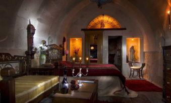 a dark and cozy bedroom with red carpet , wooden furniture , and candles , bathed in the glow of light from a chandelier at Sacred House