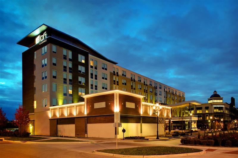 a large hotel with multiple rooms and balconies , illuminated by lights against a dark sky at Aloft Leawood-Overland Park