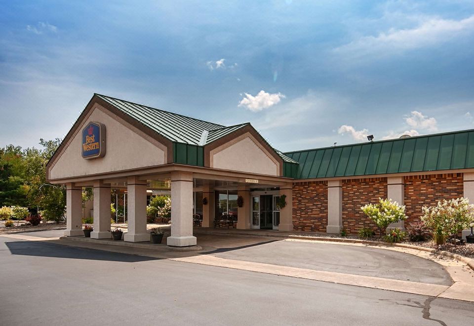 a large building with a green roof and white columns is the best western hotel at Best Western Tomah Hotel