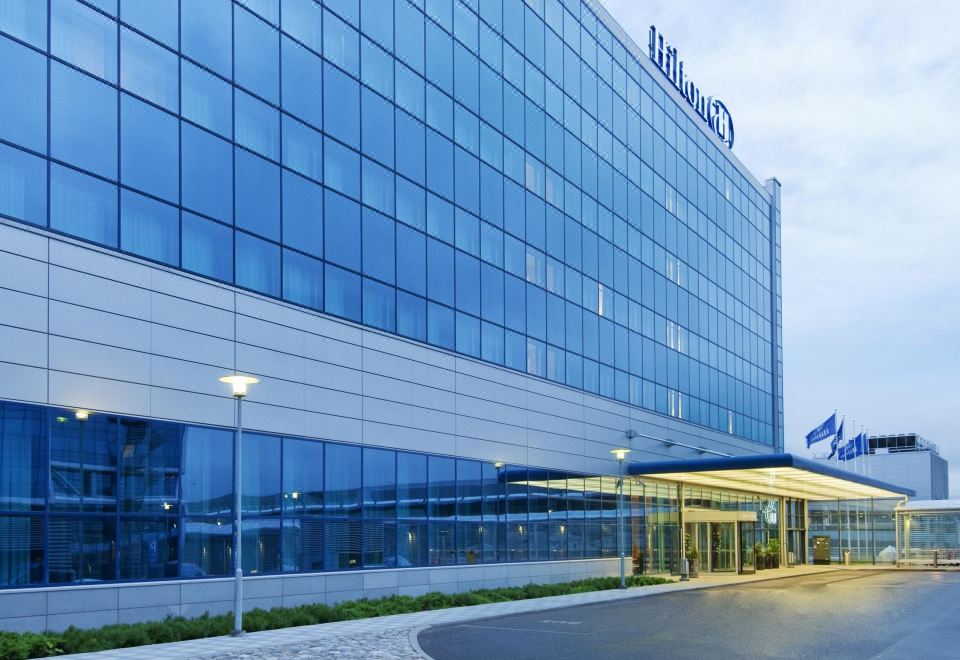 "a modern building with large windows and a sign that reads "" hilton "" on the top" at Hilton Helsinki Airport