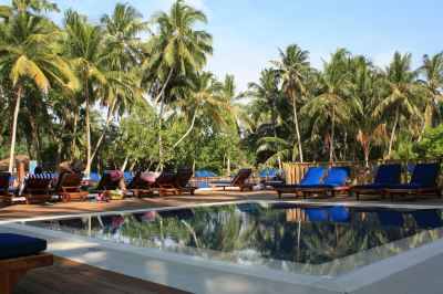a tropical resort with a large swimming pool surrounded by palm trees and blue lounge chairs at Vilamendhoo Island Resort & Spa