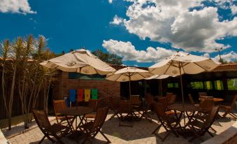 a group of people sitting under umbrellas on a patio , enjoying the outdoors and each other 's company at Brotas Eco Hotel Fazenda