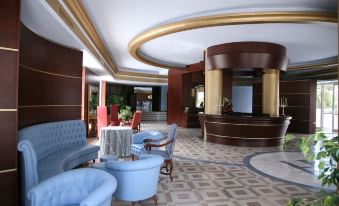 a modern hotel lobby with blue and white furniture , a reception desk , and a marble floor at Hotel Royal