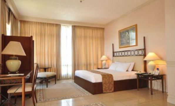 a well - decorated hotel room with a large bed , curtains , and various furniture items , including a desk , chair , and lamp at MetroCentre Hotel