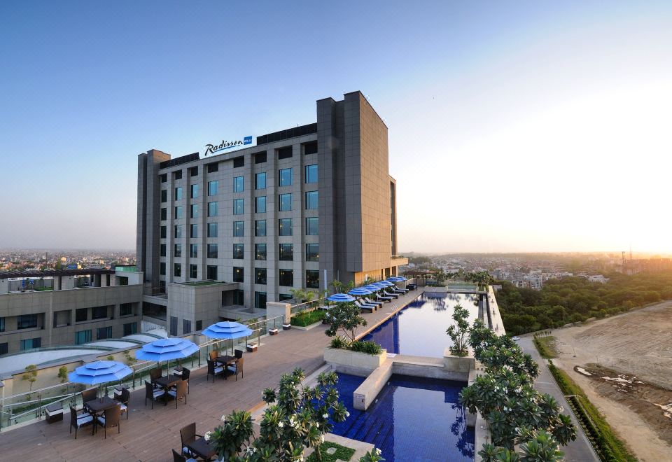 a large hotel with a pool and outdoor seating area is shown in the image at Radisson Hotel New Delhi Paschim Vihar