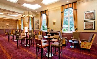 a large , well - lit room with multiple tables and chairs , creating a comfortable and inviting atmosphere at De Vere Beaumont Estate