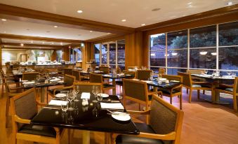 a large dining room with wooden tables and chairs , along with a window overlooking the ocean at Hyatt Hotel Canberra - A Park Hyatt Hotel