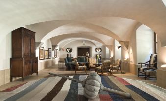 a large living room with white walls , arched ceiling , and various furniture pieces including a couch , coffee table , and dining table at Parador Monasterio de Corias