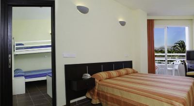a bed with a striped blanket is in a room with two wall - mounted lights and a nightstand at Club Mac Club Mac - All Inclusive Family Resort Photo