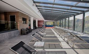 a large indoor pool area with rows of sun loungers and chairs , all under a glass roof at Eira do Serrado - Hotel & Spa