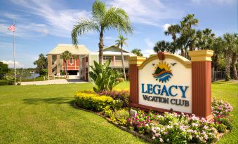 a sign for the legacy vacation club hotel is displayed in front of a tropical setting at Legacy Vacation Resorts-Indian Shores