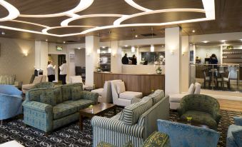 a hotel lobby with various seating options , including couches and chairs , and a bar area at Woodland Grange