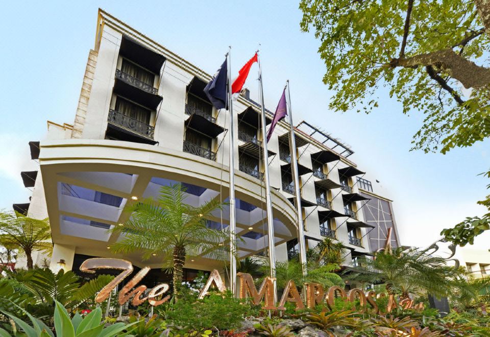 a large hotel building with multiple flags flying in front of it , surrounded by trees and greenery at Amaroossa Hotel Bandung Indonesia