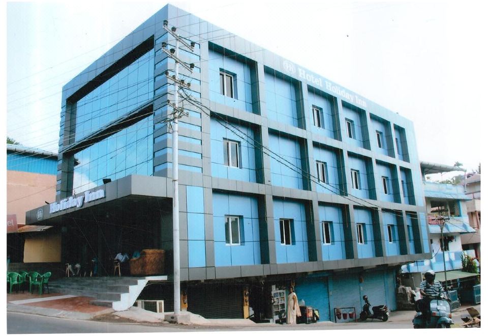 a modern building with a large glass window and blue panels , located on a street with people walking around at Holiday Inn