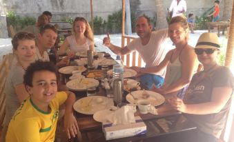 a group of people , including adults and children , are enjoying a meal together at a dining table at Paradise Lagoon