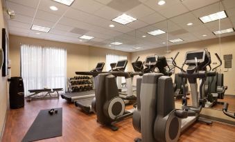 a well - equipped gym with various exercise equipment , including treadmills and weight machines , in a spacious room with wooden flooring at Hyatt Place Augusta