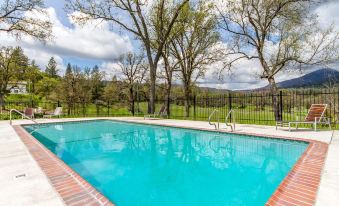 a large swimming pool surrounded by trees , with a fence surrounding the pool area and a tennis court nearby at Sierra Sky Ranch, Ascend Hotel Collection