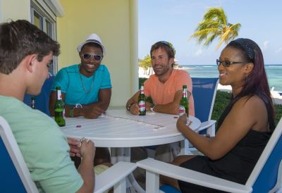 a group of people gathered around a dining table on a patio , enjoying each other 's company and drinking beer at Wyndham Reef Resort Grand Cayman