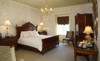 a bedroom with a wooden bed , a chair , and a chandelier hanging from the ceiling at Oheka Castle Hotel & Estate