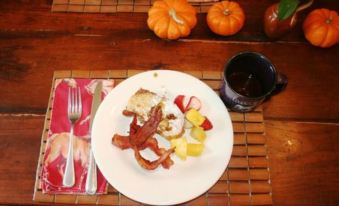 a plate of food with bacon , fruit , and a cup of coffee on a wooden table at Seventy-Four Ranch