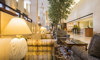 a spacious hotel lobby with multiple couches and chairs , as well as a large tree in the center of the room at Authent Hotel Otaru