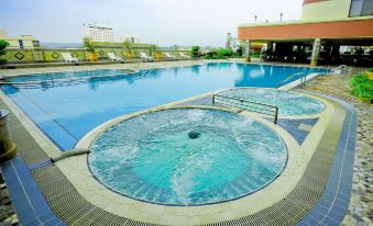 an outdoor swimming pool surrounded by a patio area , with several lounge chairs and umbrellas placed around the pool at Planet Holiday Hotel & Residence